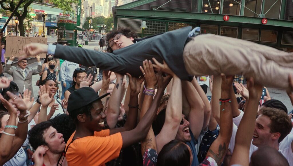 Daniel Robbins being crowd-surfed in Citizen Weiner. Celebration scene with a crowd of people.