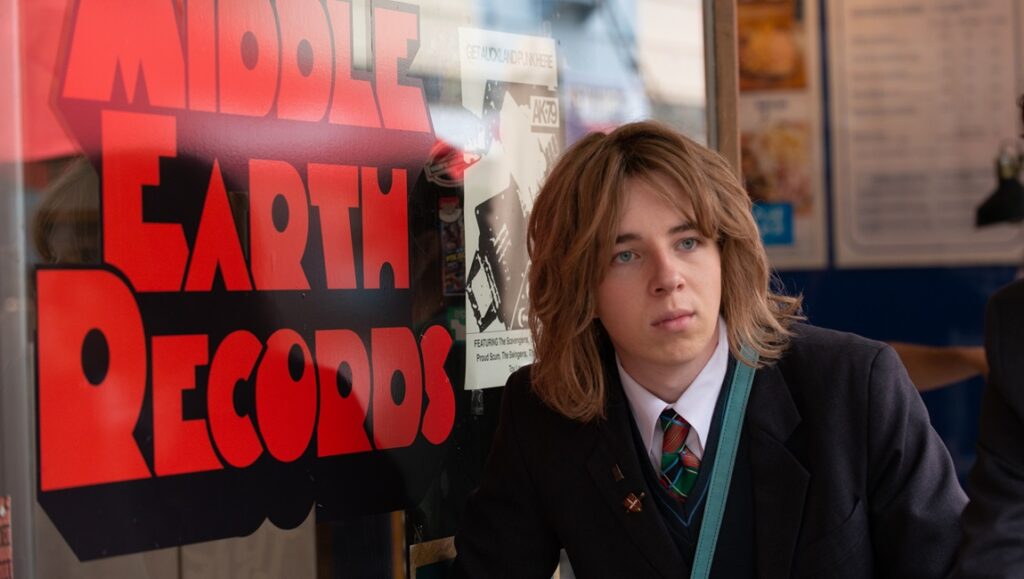 Head South IFFR 2024 film still. Young man in school uniform stands near Middle Earth Records for Rotterdam film festival.