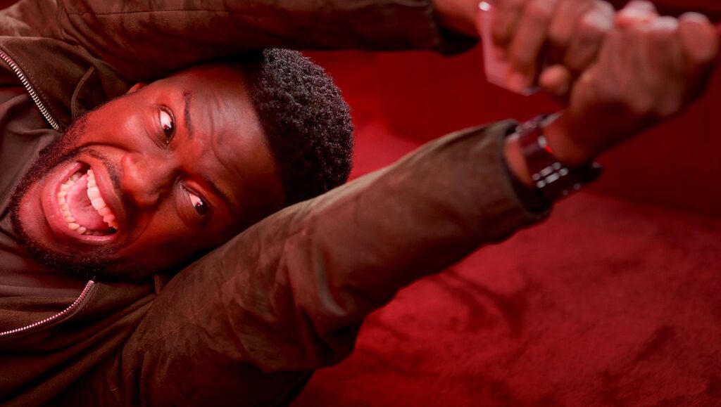 Lift movie scene: Man with intense expression. Red lighting, arms raised. F. Gary Gray film review.