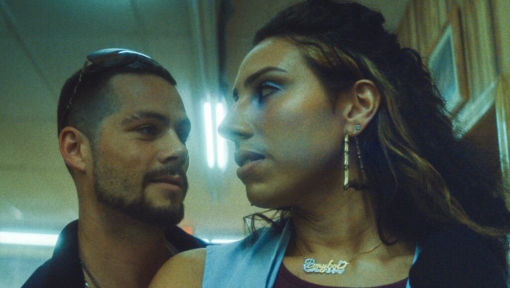 Ponyboi movie still: Dylan O'Brien and River Gallo in a close-up shot. Gallo wears a Ponyboi necklace.