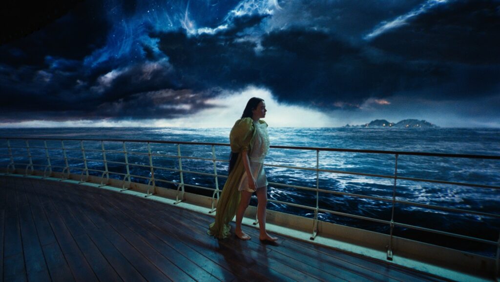 Not the Other Way Around: Poor Things, from Novel to Screen Bella Baxter in Poor Things movie. Emma Stone as Bella on a ship deck with stormy ocean backdrop.