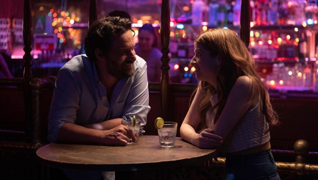 Jake Johnson in Self Reliance movie. Man and woman at a bar with drinks. Self Reliance review.