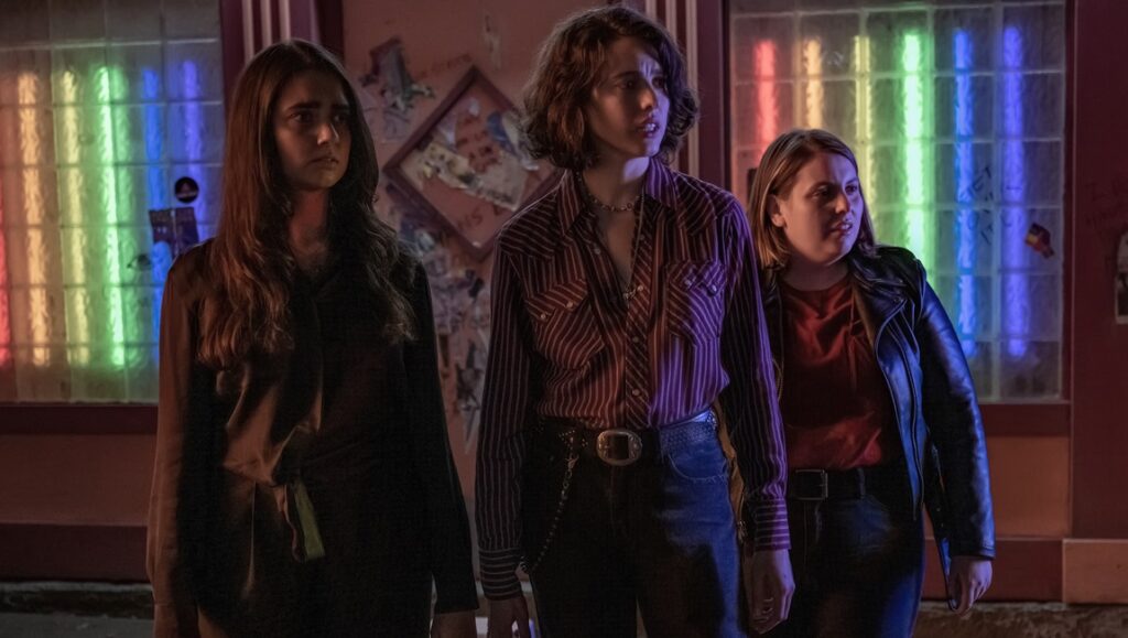 Drive-Away Dolls movie still. Geraldine Viswanathan, Margaret Qualley, and Beanie Feldstein in Ethan Coen's film.