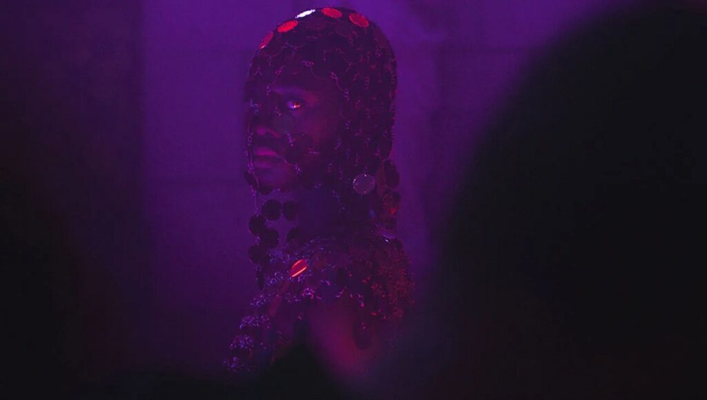 Disco Boy film still. Giacomo Abbruzzese's film features a figure in purple light, adorned with sequins.