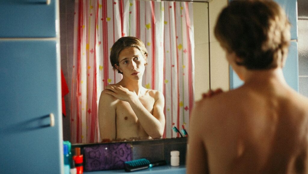 I Love You More movie scene: shirtless young man looks in bathroom mirror.