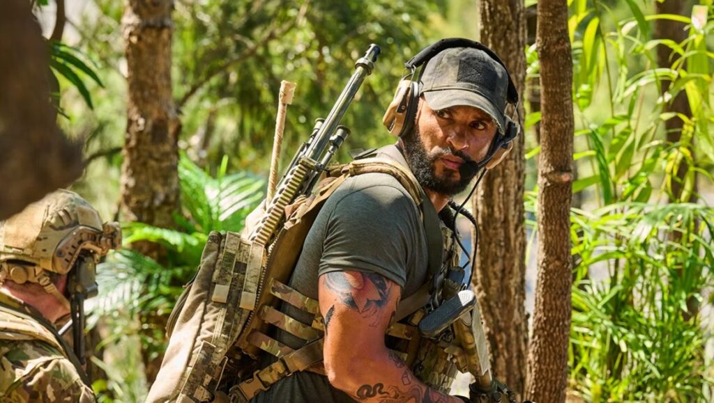Land of Bad movie image. Russell Crowe in military gear, tactical vest, and headset in a jungle setting.