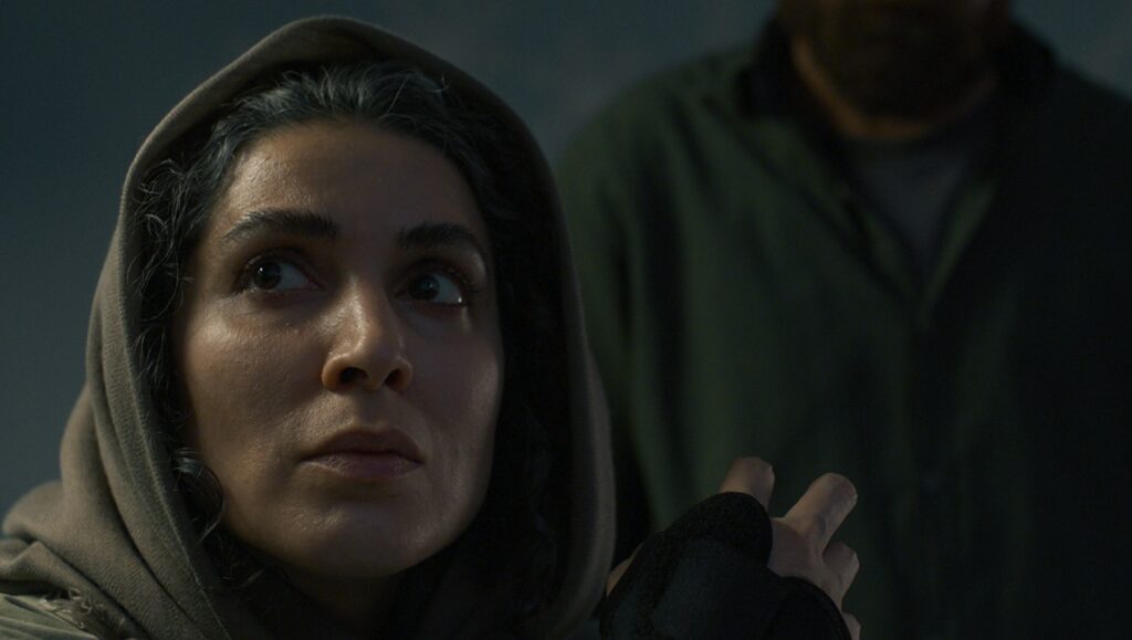 Gasoline Rainbow film review: Woman in headscarf looks up with concern. Bill Ross & Turner Ross movie scene.