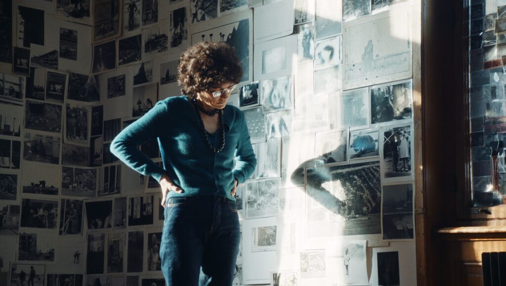 French Cinema 2024: Woman in front of wall covered in photos. The Book of Solutions film still.