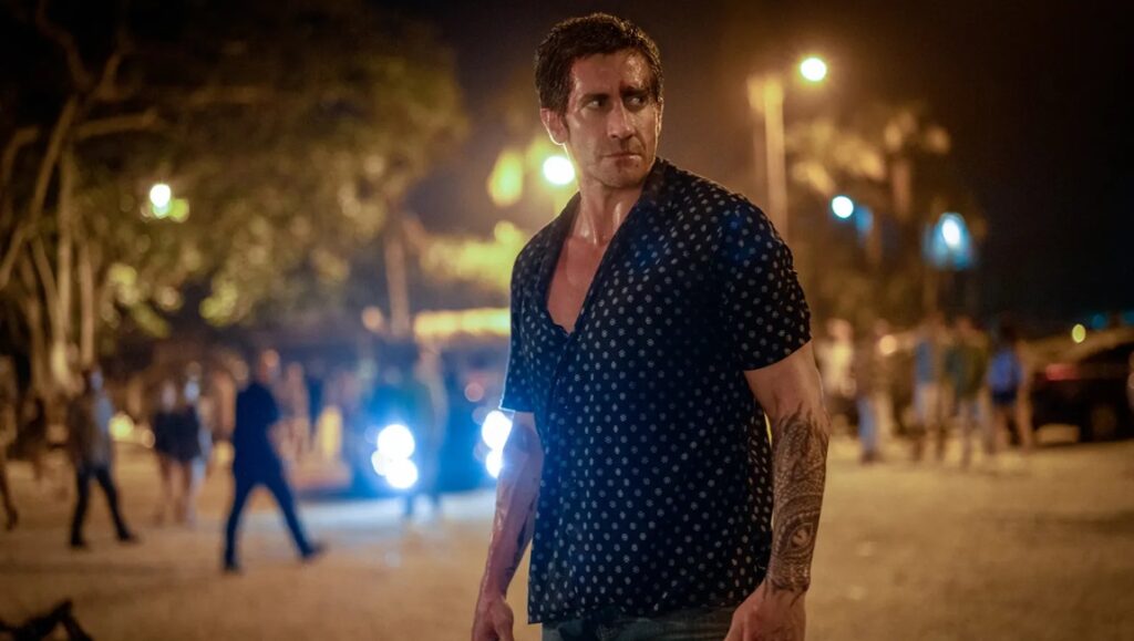 Jake Gyllenhaal in Road House (2024). Doug Liman film review. Actor with tattoos in a night scene.