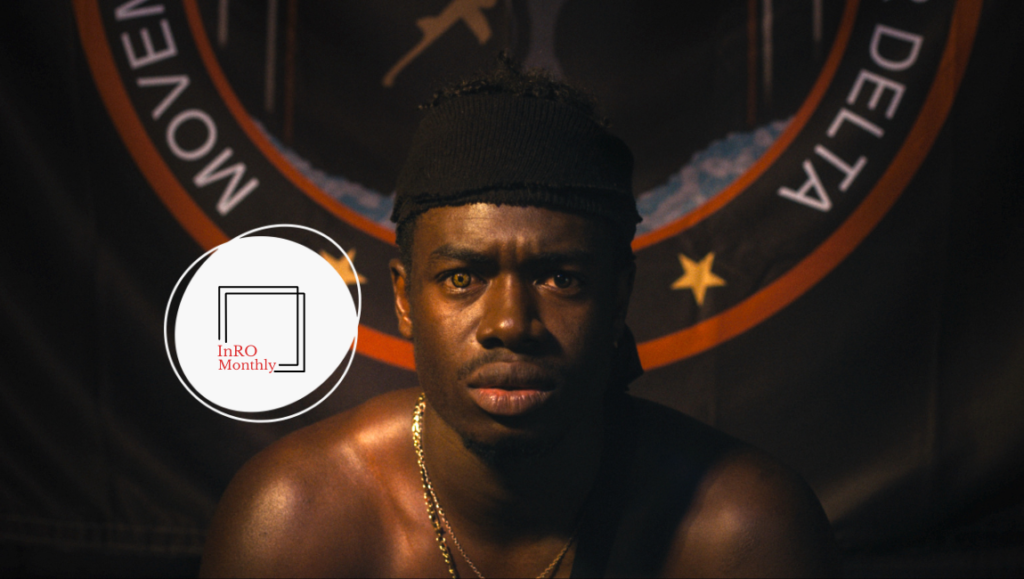 InRO Monthly February 2024 cover: Portrait of a man with a bandana and gold chain against a Movement for the Emancipation of the Niger Delta flag.