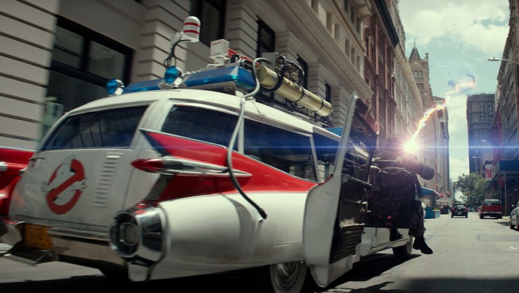 Ecto-1 in Ghostbusters: Frozen Empire. Car with ghostbusting equipment fires a beam. Action scene.