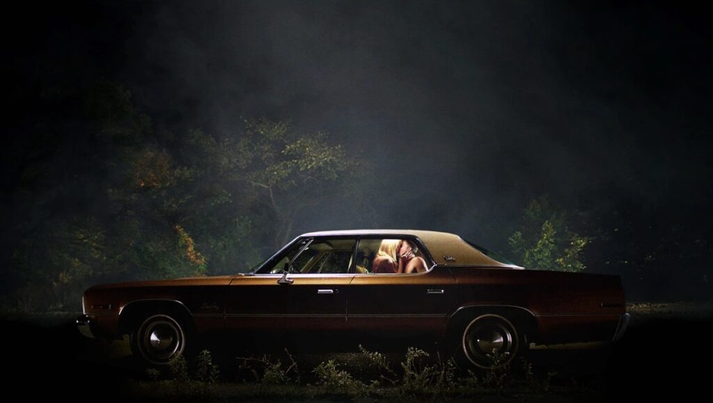 It Follows movie scene. Vintage car at night with couple inside. Horror film.
