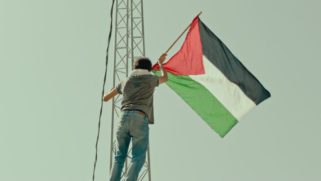 Alam movie still: Teen raises Palestinian flag on tower. Firas Khoury film review.