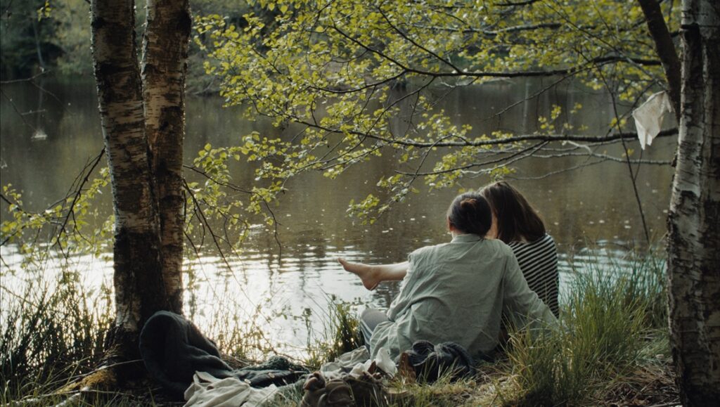 The Good Place film still: Two figures by a lake, part of New Directors/New Films 2024. Nature, indie film.