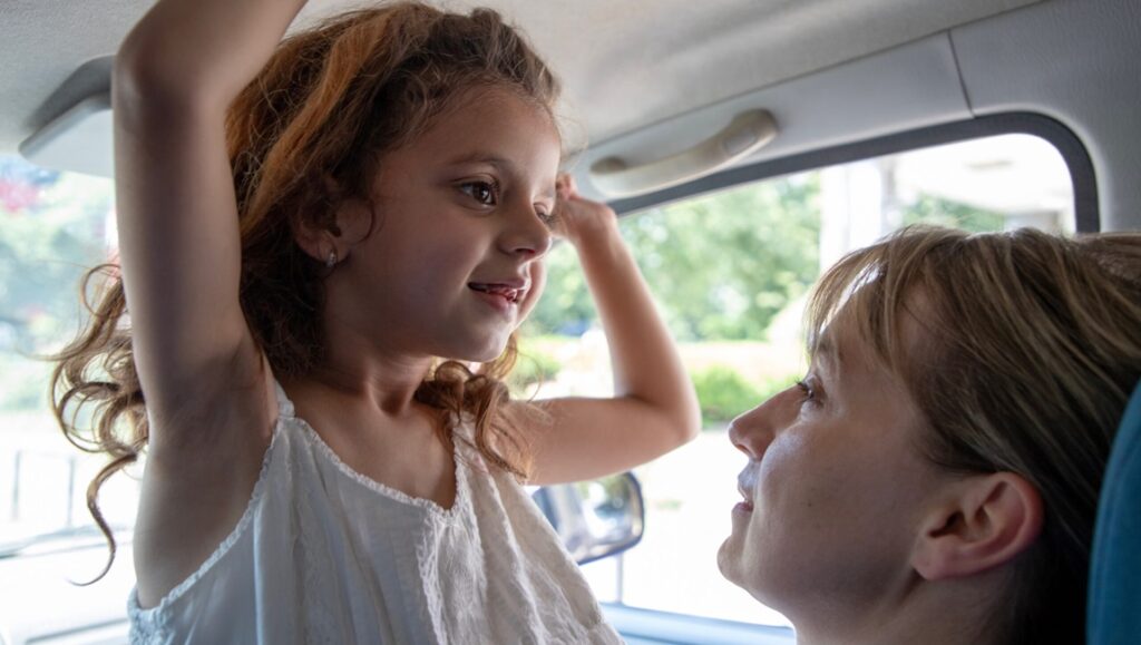 Housekeeping for Beginners film scene: A child and woman in a car, looking at each other.