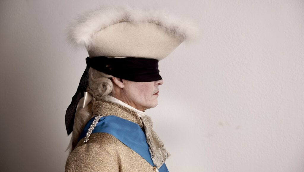 Johnny Depp as Louis XV in Jeanne du Barry. Blindfolded, in period costume. Maïwenn film.