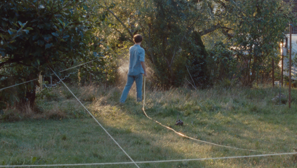 Of Living Without Illusion film still. Man in yard with rope. New Directors/New Films 2024.