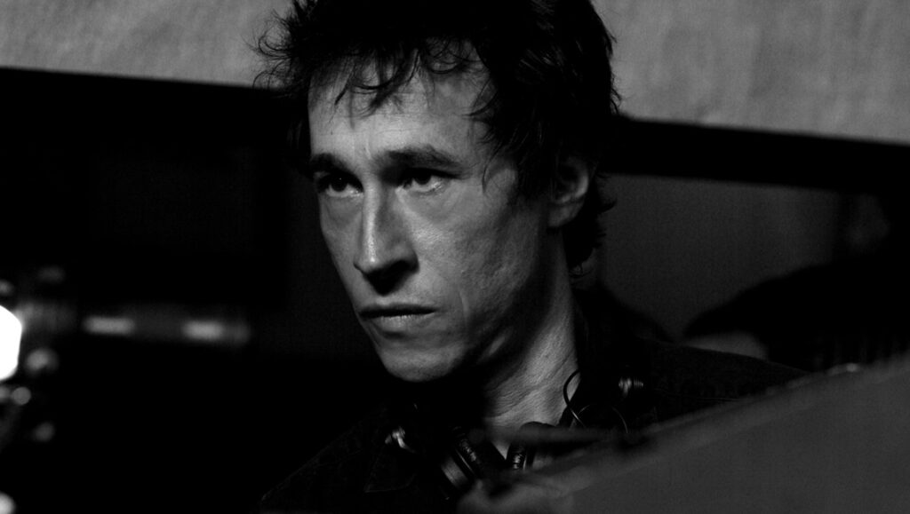 Bertrand Bonello, black and white portrait. Interview about romance in troubled times. Filmmaker with dark hair.