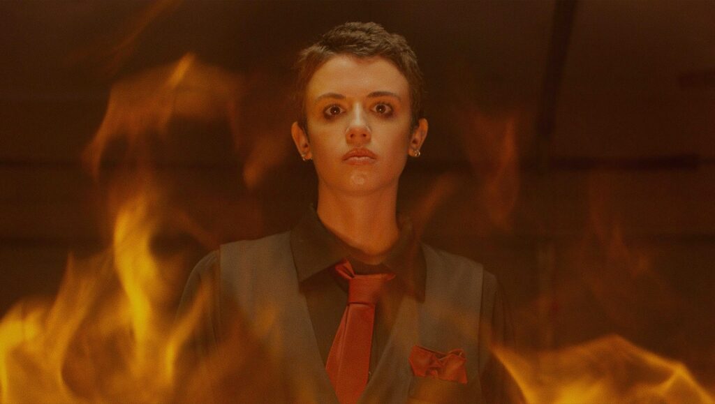 Raymond Wood in Faceless After Dark review. Person in flames, wearing a suit and tie. Horror movie scene.