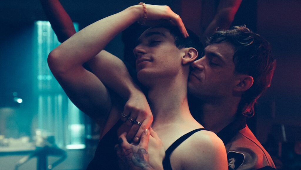 Solo movie scene. Two men embracing, one kissing the other's neck. Romantic, intimate moment.