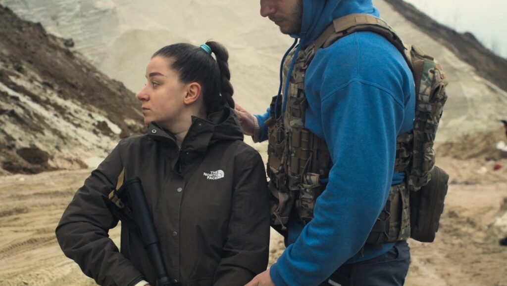 Ukrainian civilians prepare for invasion. Woman with rifle and man in tactical gear stand ready. War in Ukraine.