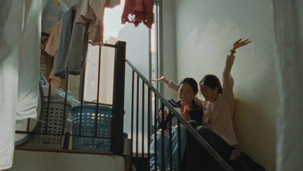 Blue Sun Palace film still from Cannes Film Festival 2024. Two women on stairs, one with raised hand.