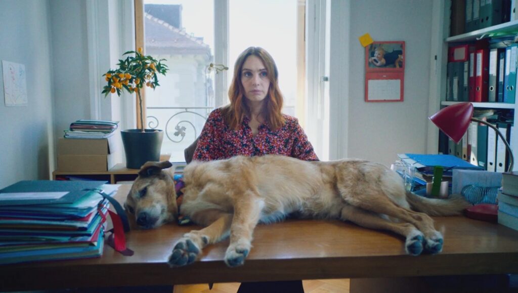 Still from Dog on Trial at Cannes Film Festival. Woman and dog on desk.