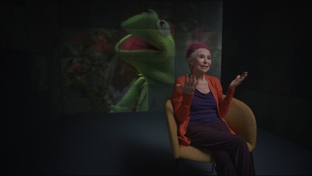 Jim Henson Idea Man: Woman sits with Kermit the Frog image. Ron Howard documentary review.