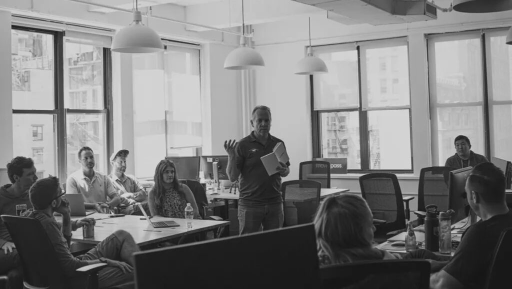 Black and white shot of MoviePass team meeting in an office space.