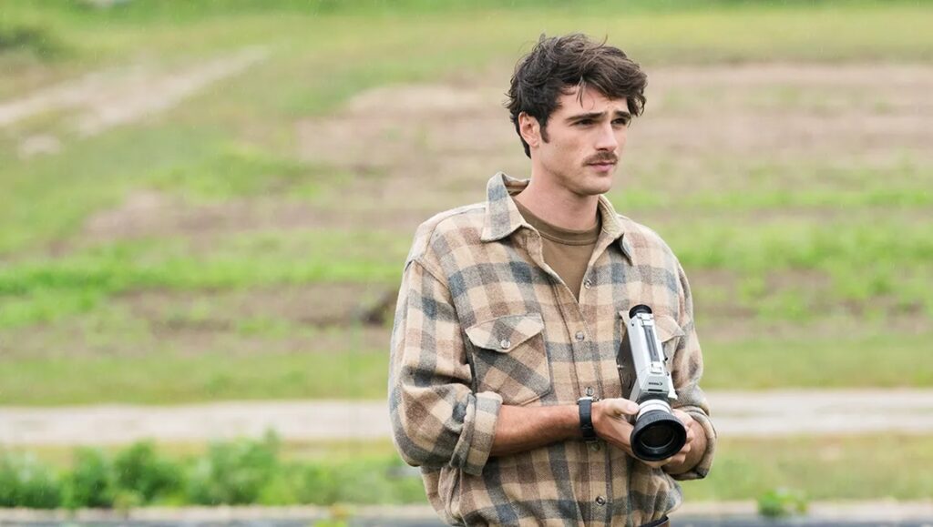Jacob Elordi in Oh, Canada at Cannes Film Festival. Elordi holds a camera, wearing a plaid shirt. Film still.