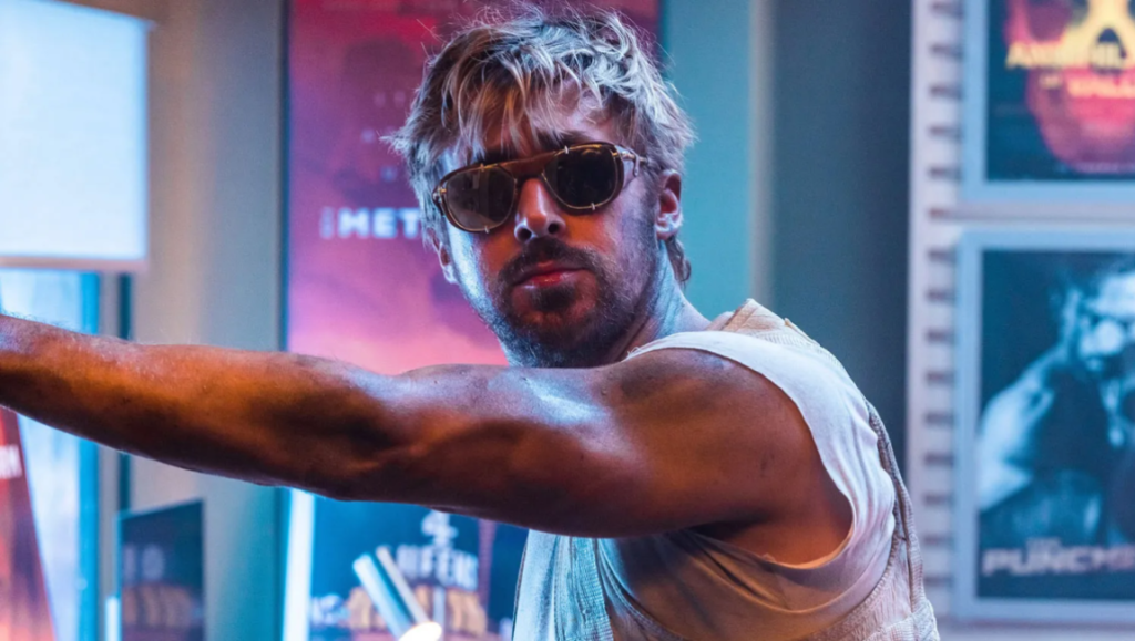 Ryan Gosling in The Fall Guy movie. Gosling wears sunglasses and a white tank top.