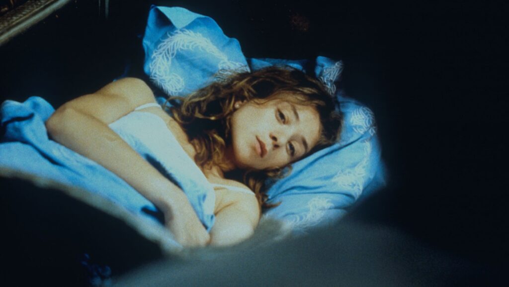 The Captive — Chantal Akerman Film still from The Captive by Chantal Akerman. Woman lying in bed with blue sheets.