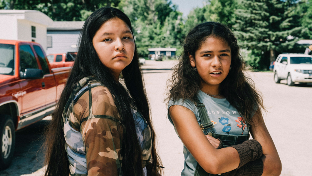 Jazzy film review: Two young Indigenous girls stand in a rural setting. Coming-of-age movie.