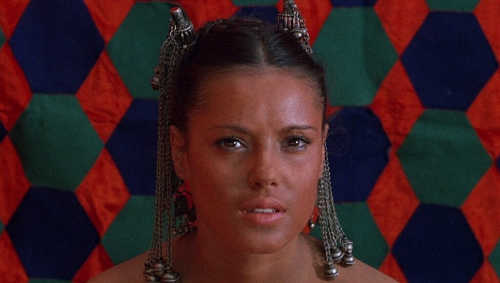 Close-up of a woman from Pier Paolo Pasolini's Arabian Nights film. Ethnic jewelry, colorful background.