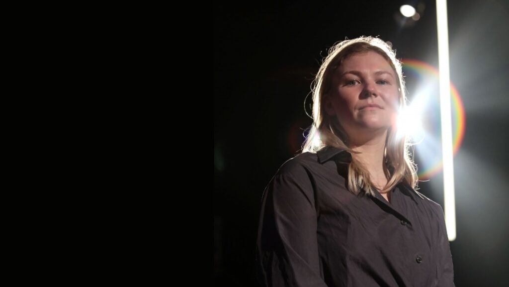 Lucy Kerr portrait. Texas filmmaker in dark shirt with bright light behind her. Interview with director.