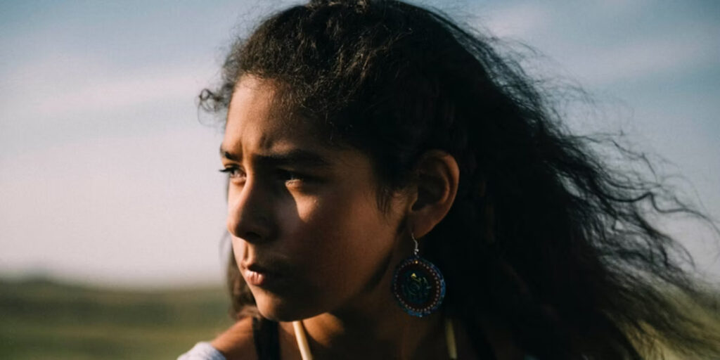 Tribeca Film Festival 2024 — Dispatch 3: Jazzy, Desire: The Carl Craig Story, Bikechess Morrisa Maltz's Jazzy film still. Close-up of a thoughtful young woman with dark curly hair and an earring.