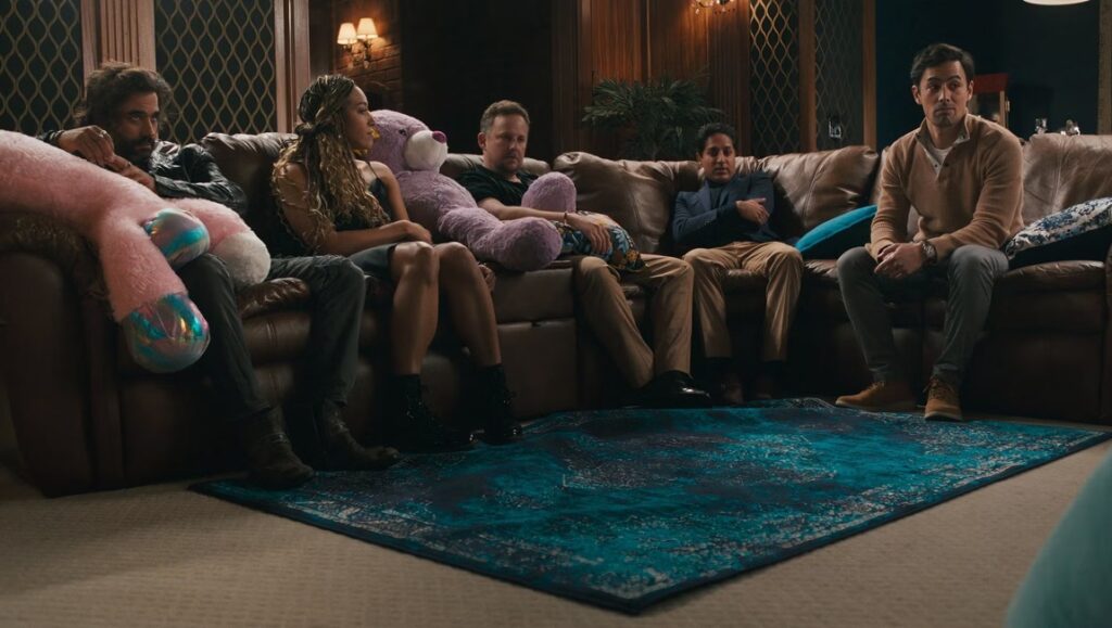 Scene from Some Rain Must Fall at Tribeca '24: Group of people on a couch with a large stuffed animal.