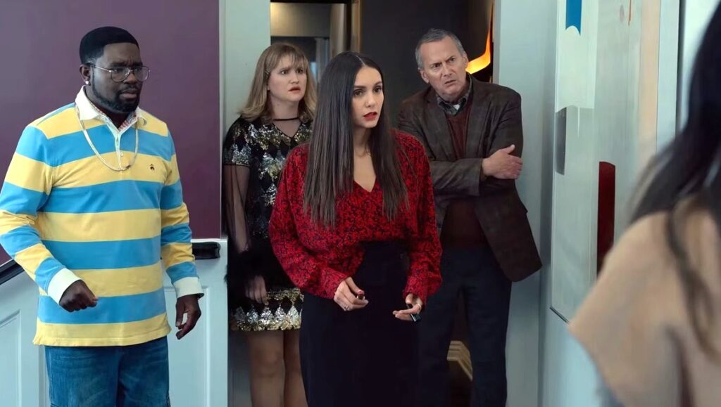 Reunion movie scene. Cast members with concerned expressions. Nina Dobrev in red sweater. Chris Nelson review.