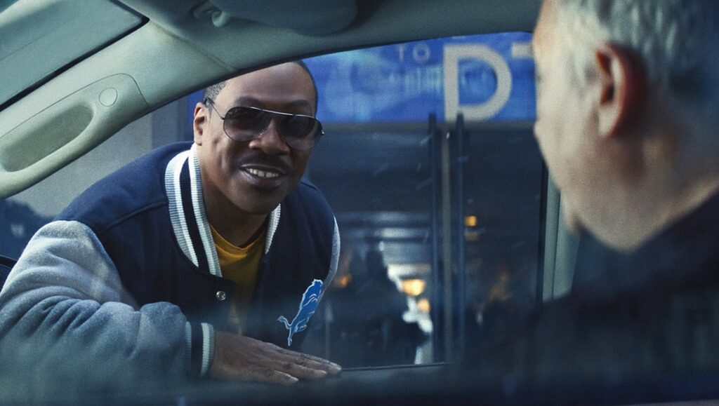 Eddie Murphy in Beverly Hills Cop: Axel F wearing sunglasses and a Detroit Lions jacket.