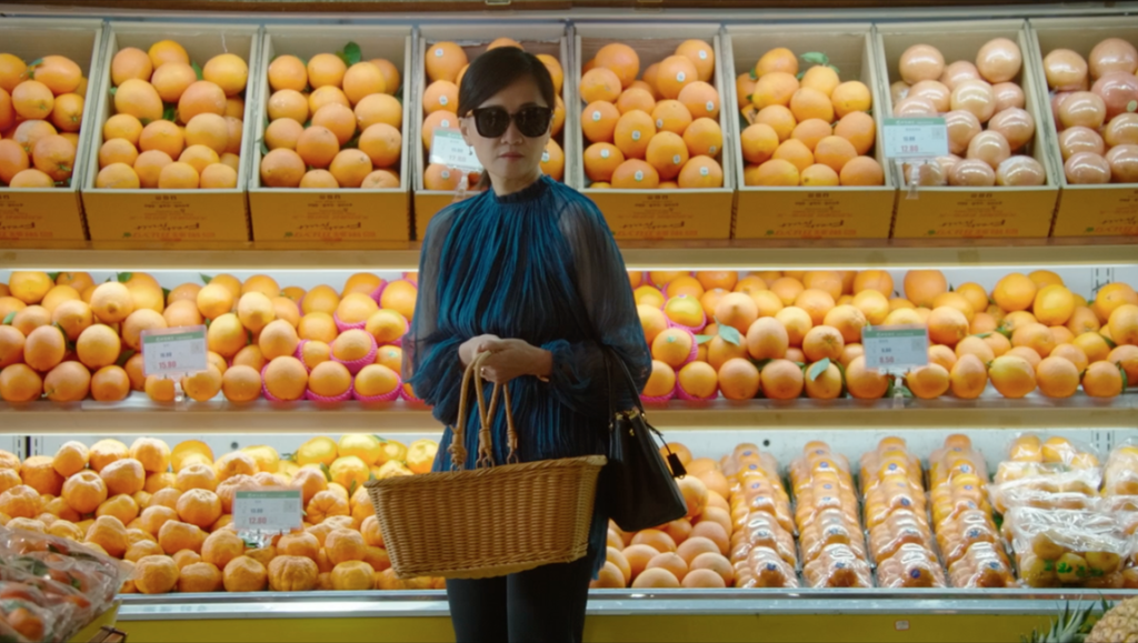 A Brief History of a Family film still: Woman with basket in front of oranges.