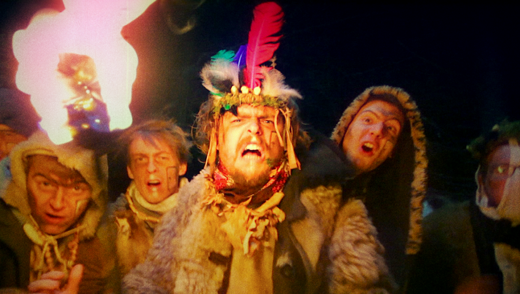 Chainsaws Were Singing film still from Fantasia Fest. Group of people in costumes, one with feathers in hair. Horror movie.