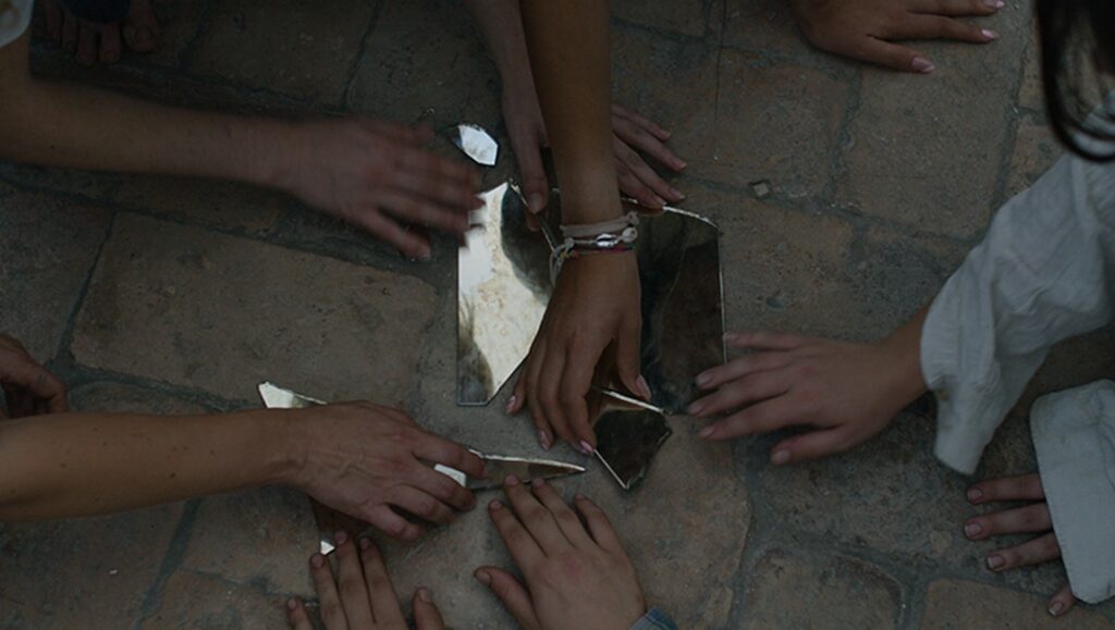 Hands touch broken mirror pieces on stone. It is at this point that the need to write history arises - Constanze Ruhm.