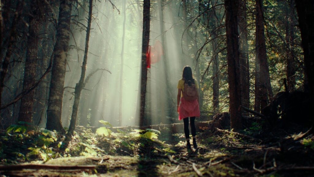 Cuckoo film still from Fantasia Fest: Woman walks into sunlit forest. Horror movie scene.