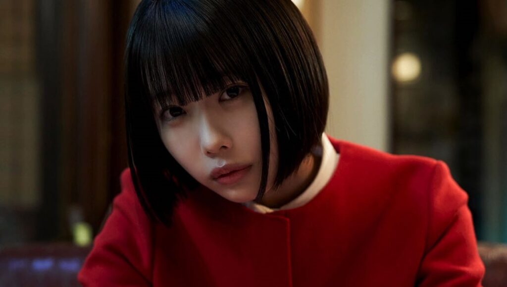 Kyrie film review: A young woman with black hair and a red jacket stares intently. Japan Cuts '24.