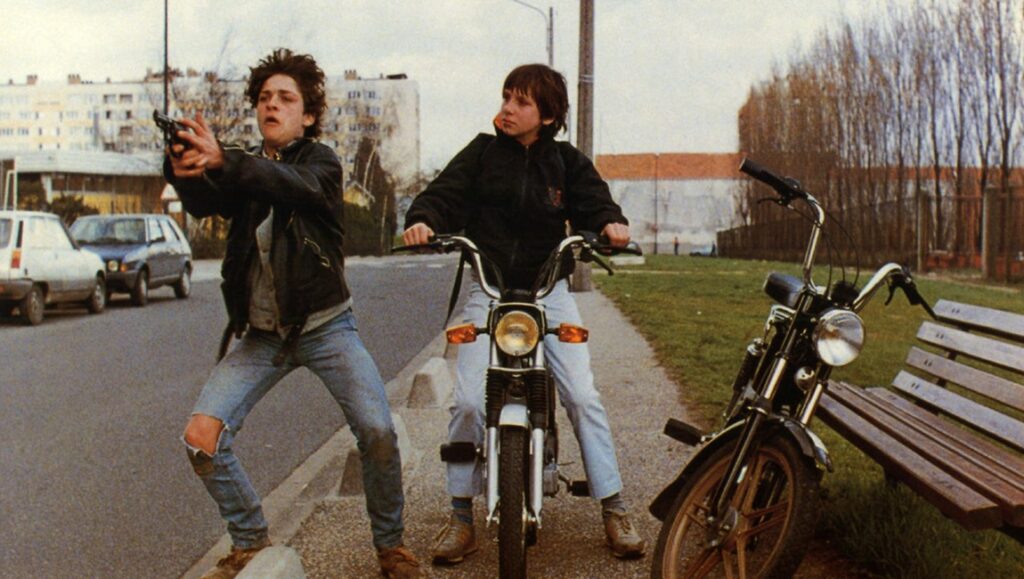 Sound and Fury 1988 film scene. Two young men, one with a gun, next to motorcycles. 80s movie.