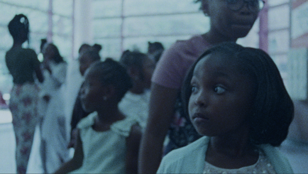 Daughters film review: Young girls at a gathering, focus on a girl looking to the side.