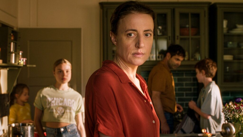 Der Spatz im Kamin film still from Locarno Film Festival 2024. Woman in red shirt with family in kitchen.