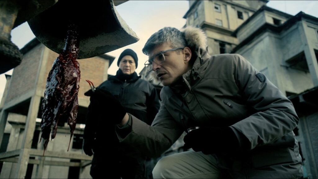 Hell Hole film still from Fantasia Fest. Two people examine a bloody object hanging from a structure.