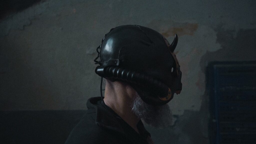 Bob Basset helmet from Rule of Two Walls review. Man wearing a black helmet with horns in a dark room.