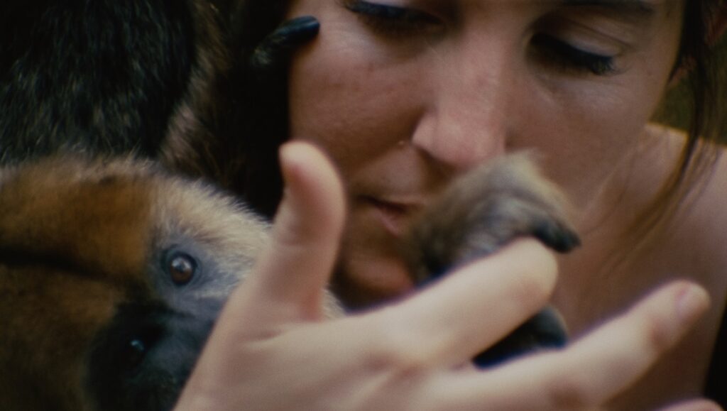Collective Monologue film still from Locarno Film Festival. Woman holding a baby monkey.